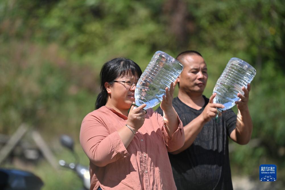 楊寧（左）在查看村民剛剛采集的水樣，為山泉水引水工程做準(zhǔn)備（10月8日攝）。新華社記者 黃孝邦 攝